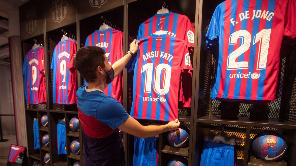 Un empleado de la Barça Store Camp Nou coloca la nueva camiseta del delantero del Barcelona, Ansu Fati, que se convierte en el heredero del dorsal 10 de Leo Messi