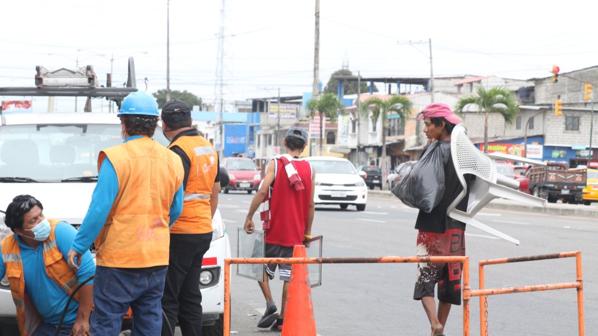 Labor. Los técnicos de CNT reemplazan los cables que se han robado en la avenida Juan Péndola, al sur de la urbe, mientras pasan dos recicladores.