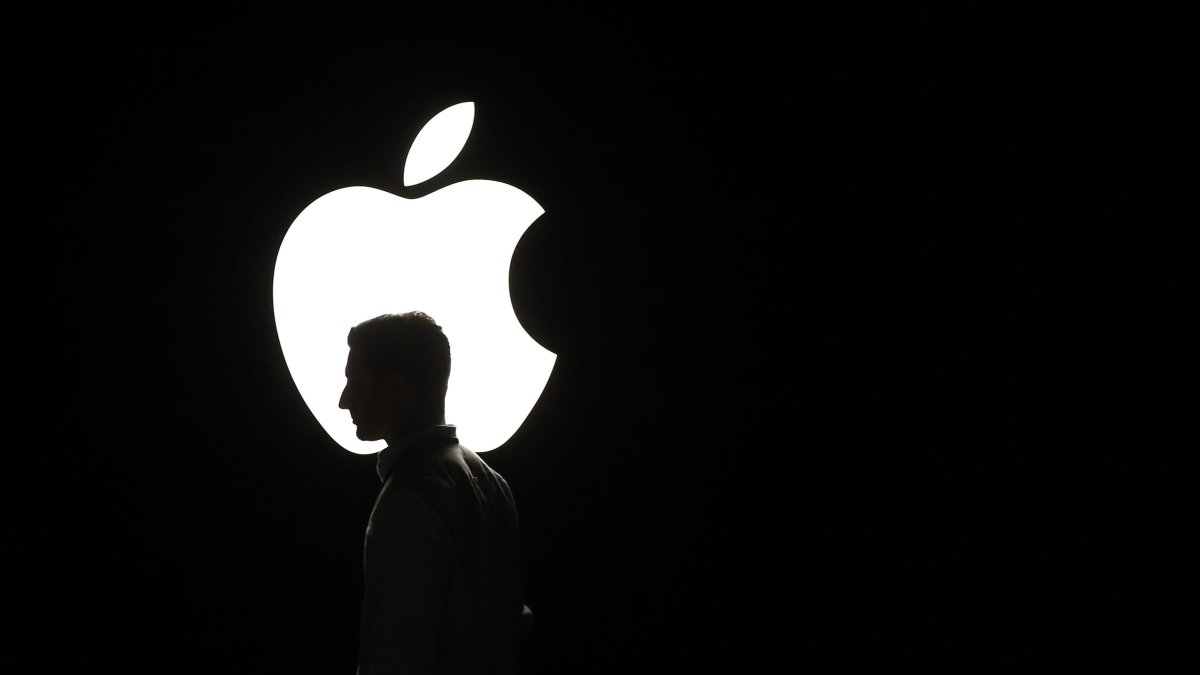 La silueta de un hombre se ve frente al logo de Apple, en una fotografía de archivo.
