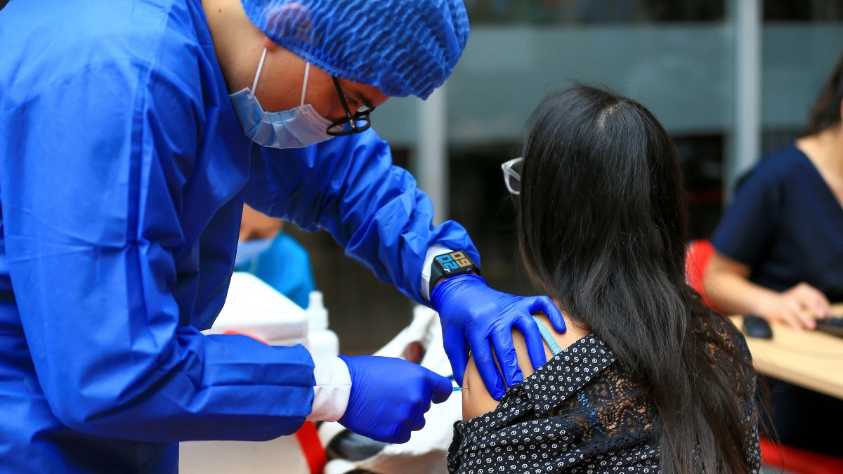 Fotografía de archivo en la que se registró a una mujer al ser vacunada contra la covid-19, en la Universidad de Las Américas, en Quito (Ecuador).