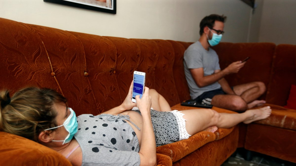 Imagen de archivo de dos jóvenes revisan sus teléfonos celulares dentro de su casa durante la cuarentena por la pandemia de covid-19 en La Habana (Cuba).