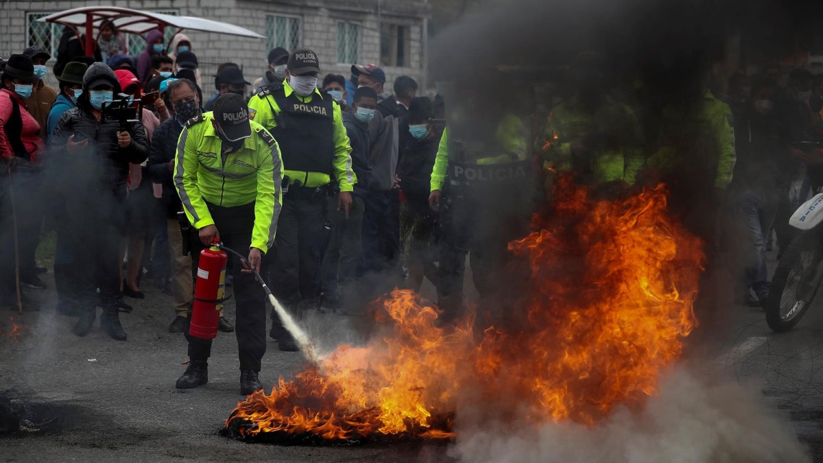 Policías intentan extinguir el fuego de unas barricadas en una carretera, encendido por indígenas que protestan para exigir la derogación del alza en los precios de los combustibles, en Pujilí, provincia de Cotopaxi (Ecuador).