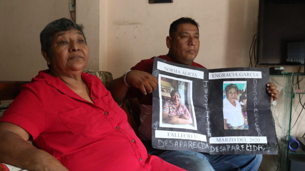 Reclamo. Roberto Farías muestra, junto a su tía, un cartel con la foto de su madre saparecida desde la pandemia.