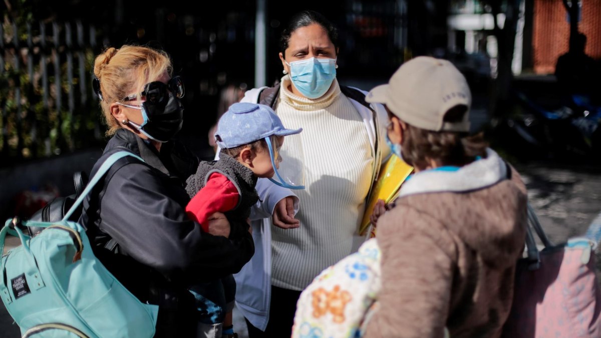 Venezolanos esperan antes de abordar un bus hoy viernes, frente al consulado de su país en Quito.