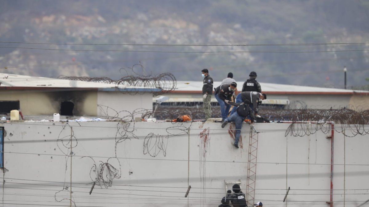 Sobre un muro del pabellón 2 se observa cómo se realizan pericias alrededor de un cadáver.