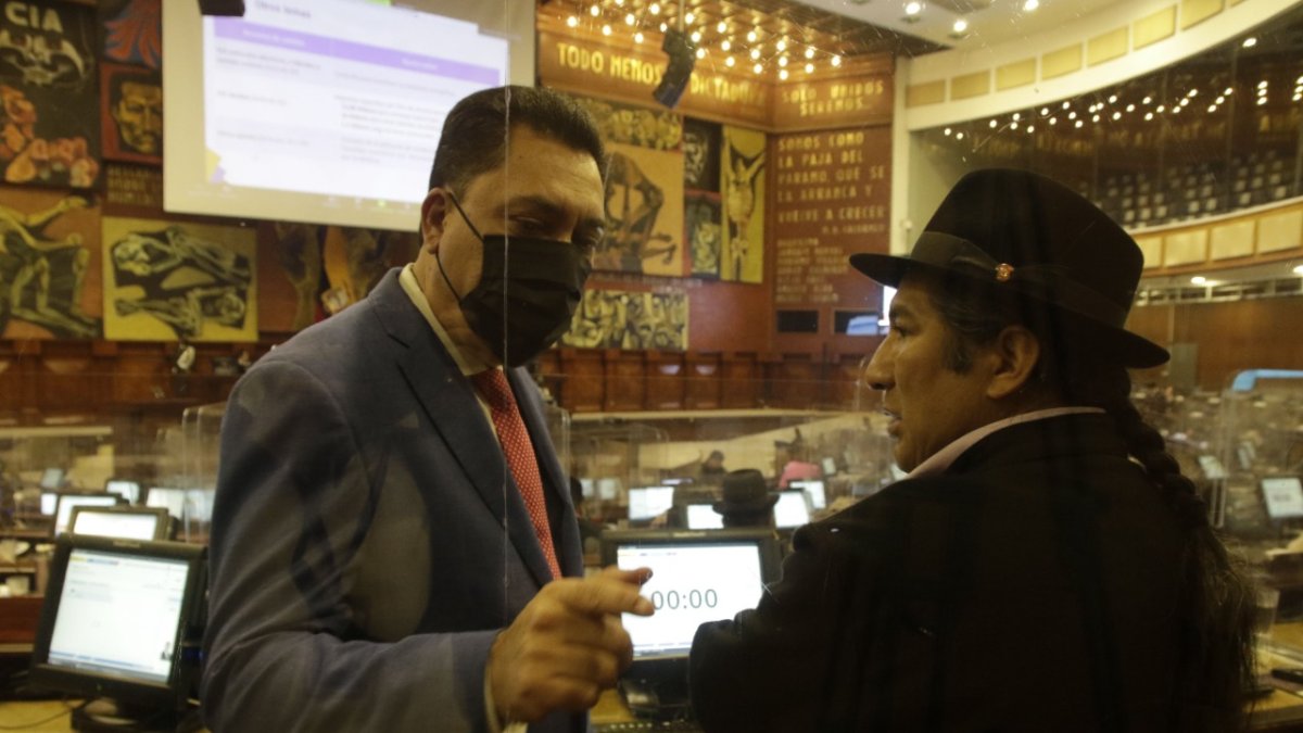 El asambleísta correísta Carlos Zambrano dialoga con su colega de Pachakutik, Salvador Quishpe durante la lectura del informe de primer debate.