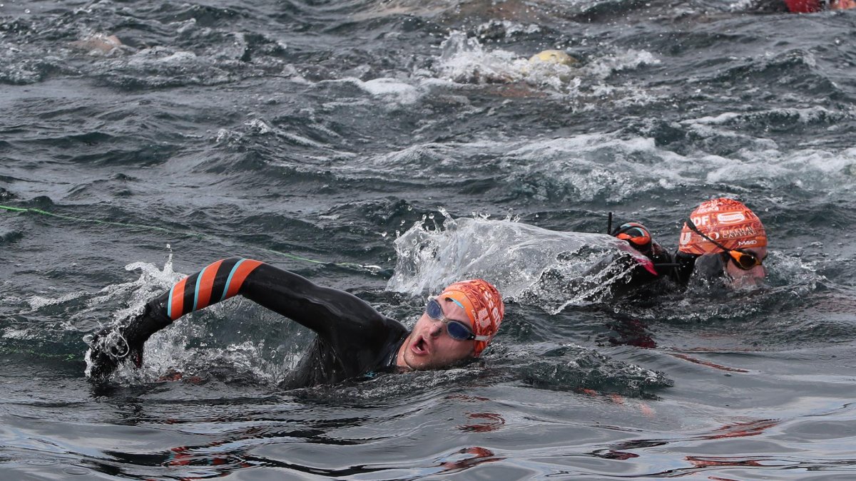 Los franceses Théo Curin (d), nadador y medallista paralímpico, y Matthieu Witvoet, quien recorrió una veintena de países en bicicleta en 2017 descubriendo soluciones locales a los residuos plásticos, halan, el 10 de noviembre de 2021, el bote en el que se encuentra su compatriota Malia Metella.