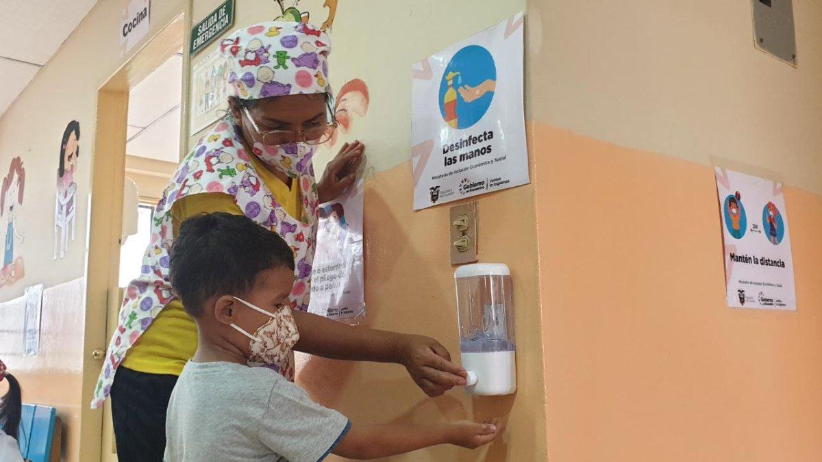 Uno de los niños de un Centro de Desarrollo Infantil de Samborondón que abrieron esta semana, utiliza el dispensador de gel desinfectante junto a una maestra.