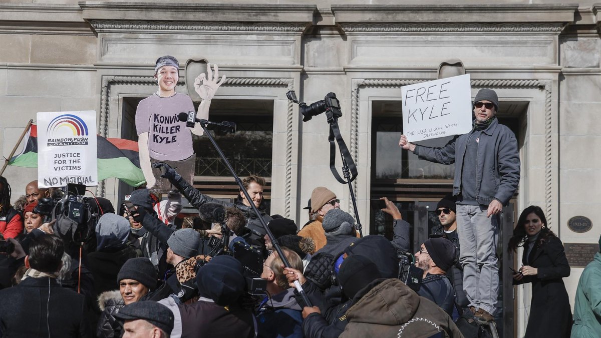 Brandon Lesco (d) sostiene un cartel en oposición fuera del juzgado del condado de Kenosha mientras el jurado declara no culpable de los cinco cargos en el juicio de Kyle Rittenhouse en Kenosha, Wisconsin (EE.UU.).