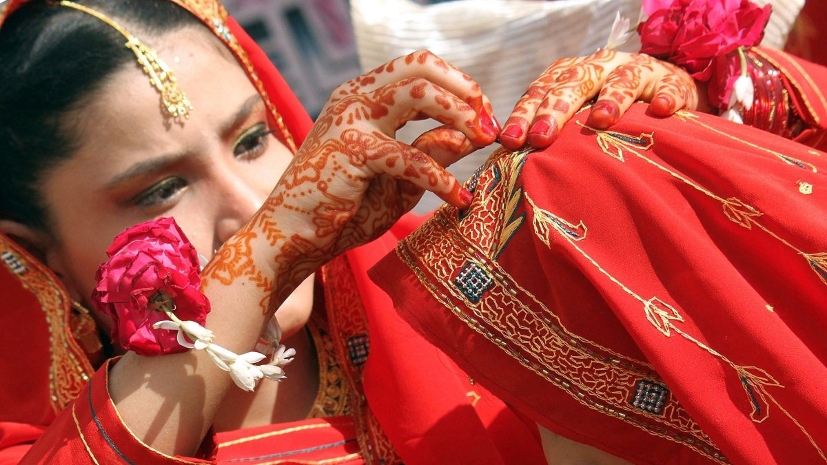 Dos novias se ayudan a colocar el pañuelo durante su ceremonia matrimonial múltiple en Karachi (Pakistán). Rehan  Kahan