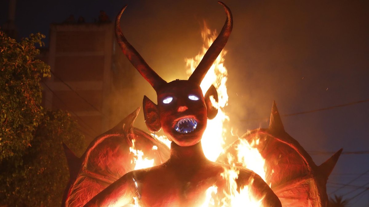 Fotografía de un diablo de papel y metal de cinco metros y 400 libras quemándose como un signo de protesta por el mal manejo de la pandemia de parte del presidente Alejandro Giammattei, hoy en Ciudad de Guatemala (Guatemala).