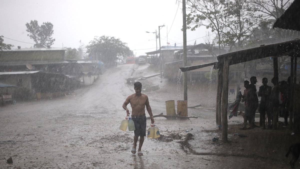  Un migrante lleva bajo intensa lluvia un bidón de agua potable a un depósito que sirve de refugio para migrantes en el Tapón del Darién. / Mauricio Valenzuela/