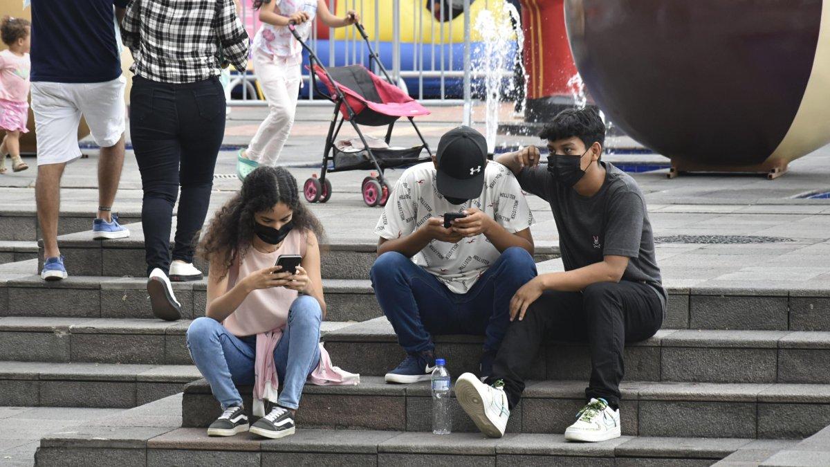 Jóvenes guayaquileños en el Malecón Simón Bolívar, todos mantienen fija la mirada en su dispositivo.
