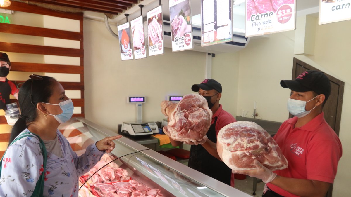Comercio. Una cliente selecciona una pierna de cerdo en uno de los locales de Servicárnicos, en la Alborada.