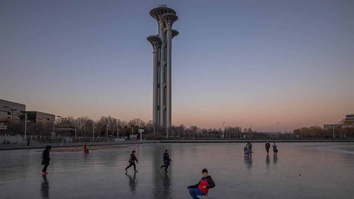 Varias personas patinan en el canal situado ante la Torre Olímpica cerca de las instalaciones deportivas para los Juegos Olímpicos de Invierno de Pekín 2022, en Pekín, China.
