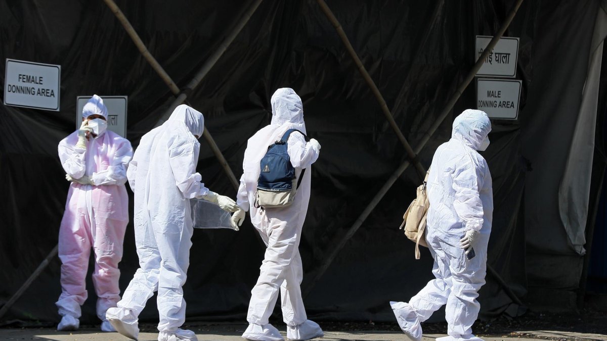 Health workers wearing personal protective equipment walk past a quarantine centre in Mumbai, India, 20 January 2022.