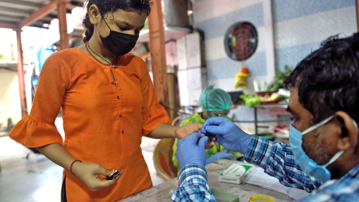 Un sanitario toma una muestra de sangre a una joven para detectar malaria y dengue en Mumbai / El País