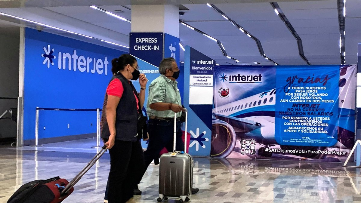 Espera. Dos personas pasan frente a un mostrador de Interjet en el aeropuerto de Ciudad de México. Miles llevan un año sin volar en esta aerolínea.