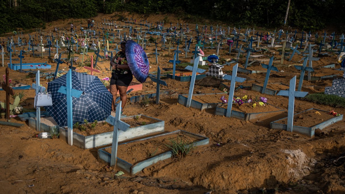 Personas se protegen del sol mientras visitan las tumbas de familiares en el área destinada a las víctimas del Covid-19 en el cementerio Nossa Senhora Aparecida, en Manaos, en una fotografía de archivo.
