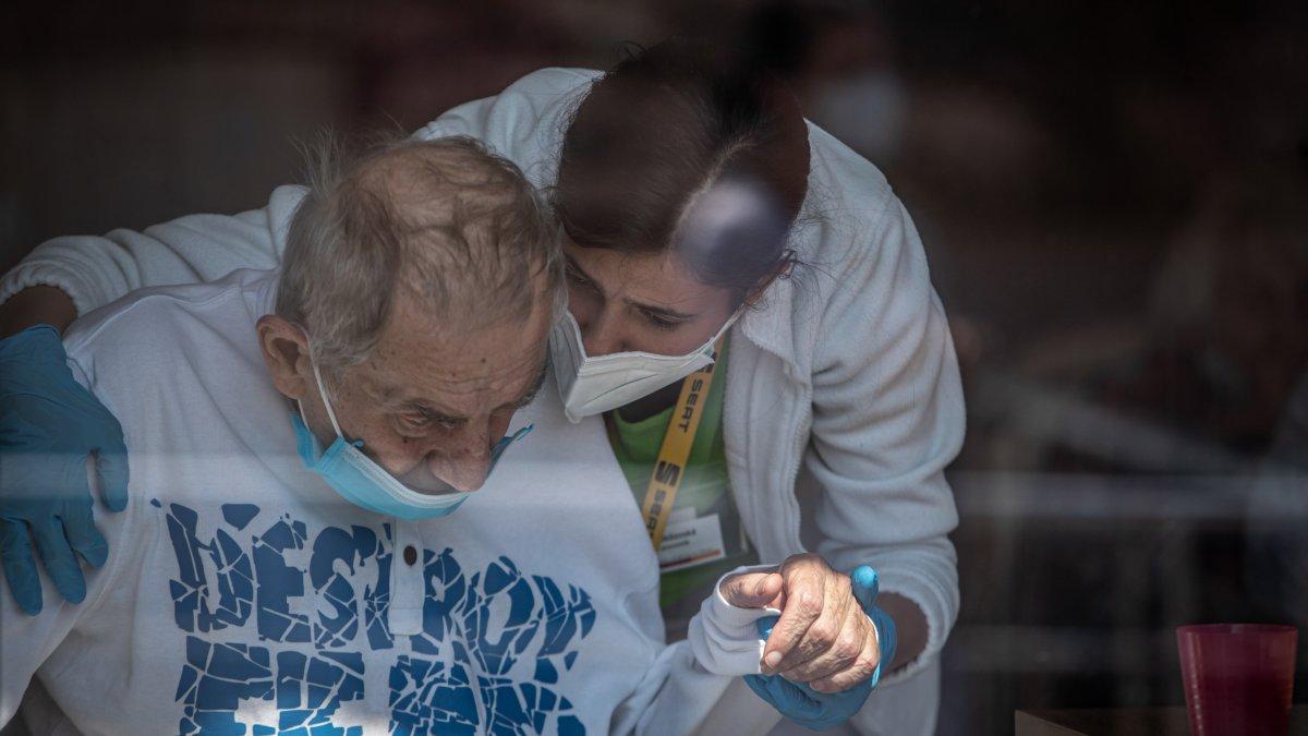 Un sanitario con mascarilla sostiene la mano de un residente de una casa de Alzheimer en Pitkovice,