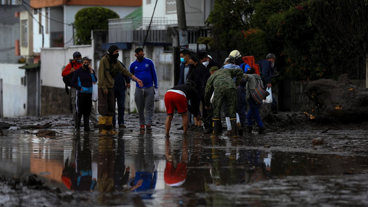 Vista de personas mientras ayudan en la labor de limpieza sobre el lodo ocasionado por las lluvias del día anterior, que afectó algunos barrios del oeste de la capital ecuatoriana, este 31 de enero de 2022.