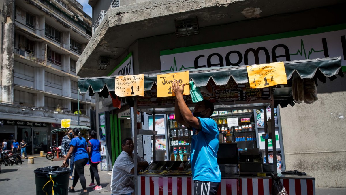 Un vendedor ambulante organiza letreros con precios de alimentos, en Caracas (Venezuela). Este y otros países de la región han recurrido al dólar como moneda de pago. 