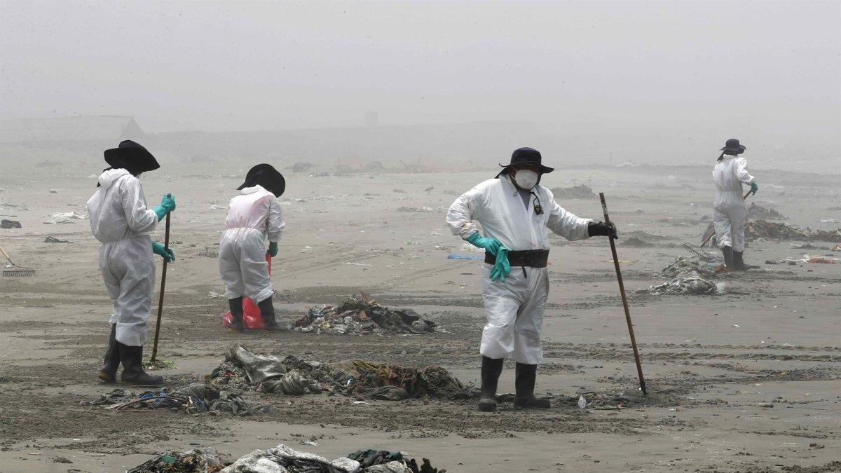 Personal de limpieza limpia y recoge basura, hoy en la playa Cavero en el distrito de Ventanilla en Lima (Perú).