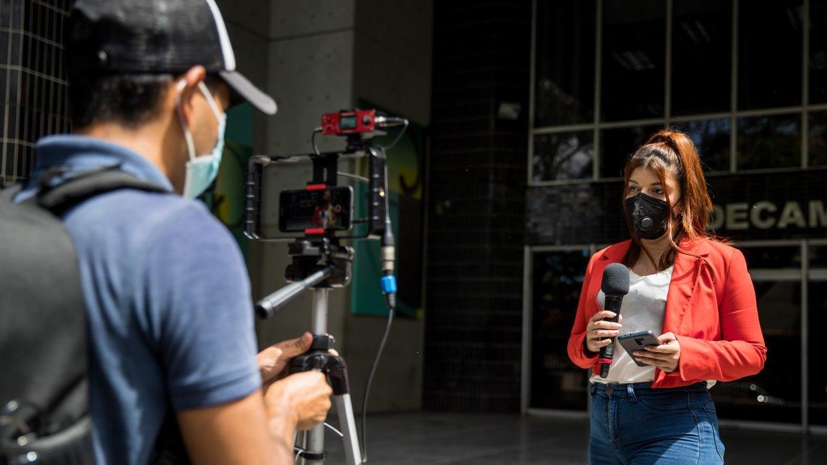 Fotografía fechada el 4 de febrero del 2022 donde se observa a una periodista de un portal privado de noticias en internet mientras hace un reporte, en Caracas