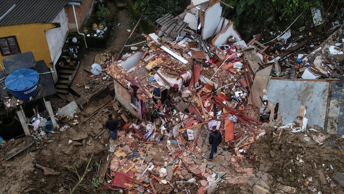 Fotografía tomada con un drone que muestra a dos hombres junto a una vivienda destrozada en medio de la destrucción tras las fuertes lluvias del martes en el Morro de la Oficina, el 18 de febrero de 2022, en la ciudad de Petrópolis, estado de Rio de Janeiro (Brasil).