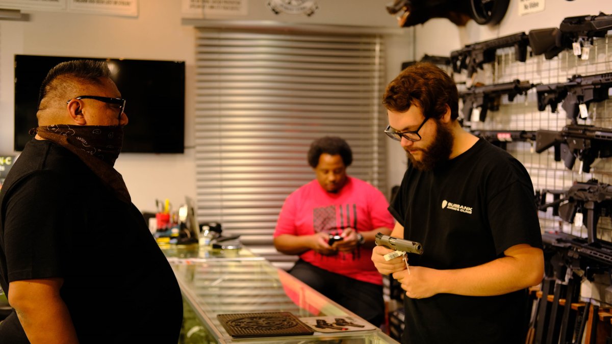 Un vendedor de la armería ‘Ammo and Guns’ muestra un revólver a un cliente.