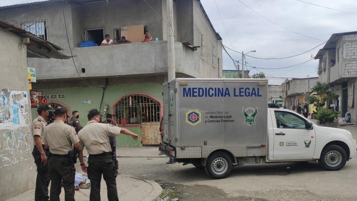 Policías rodean el cuerpo de la víctima que ha sido cubierto con una sábana.