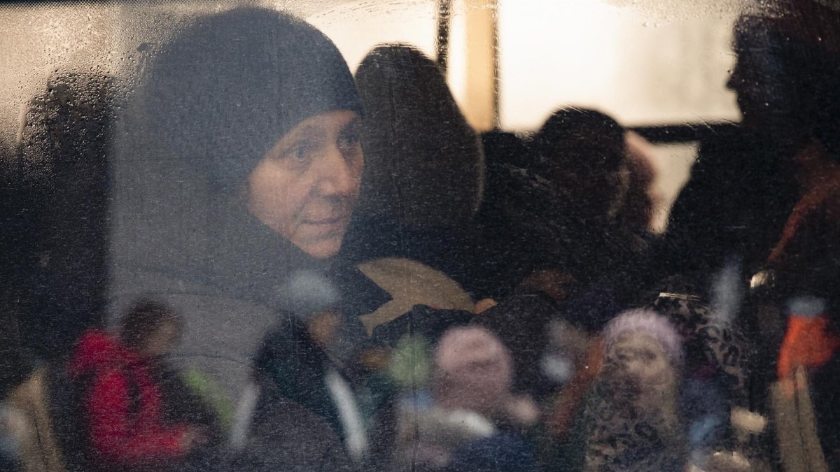 Una mujer, vista a través de la ventana de un autobús, observa durante la evacuación de civiles a Kiev, llevada por combatientes de defensa territorial, en la pequeña ciudad de Irpin, cerca de Kiev.