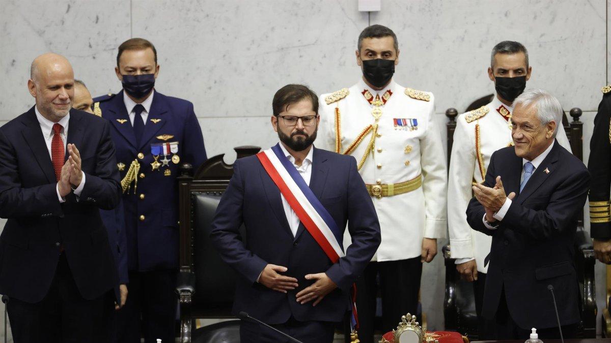 El presidente de Chile Gabriel Boric saluda a los asistentes al Congreso Nacional luego de recibir la banda presidencial del senador socialista Álvaro Elizalde (izq.), mientras el expresidente Sebastián Piñera (der.) aplaude hoy en Valparaiso (Chile).