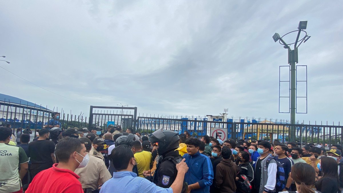 Los aficionados pugnan por ingresar a la explanada del estadio Modelo Alberto Spencer Herrera para comprar un boleto, mientras la policía intenta preservar el orden. 