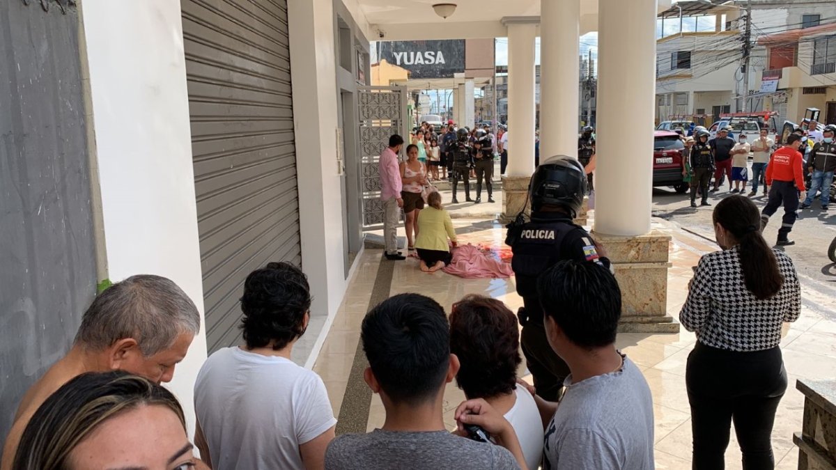 Familiares lloran junto al cadáver de la víctima, Cumandá Sánchez Benítez, luego de cubrirla con sábanas, en la entrada de su casa.