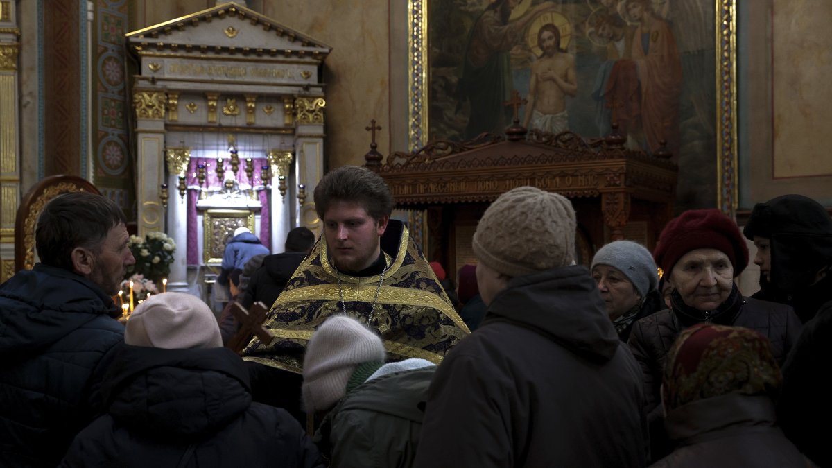 Uno de los sacerdotes de la Catedral Svyato-Uspensky, de la Iglesia Ortodoxa Ucraniana, ofrece una cruz a los fieles para que la besen durante el oficio. EFE