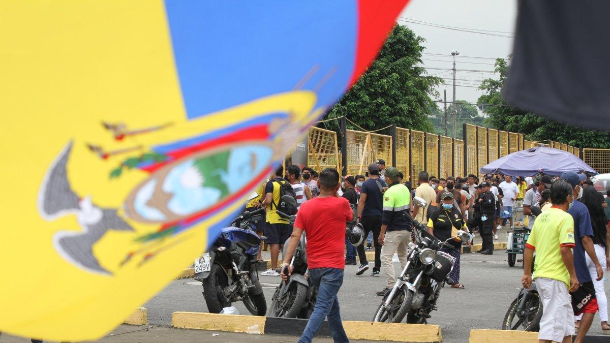 Una bandera de Ecuador y de fondo compradores de boletos para el partido entre Ecuador y Argentina en el Monumental