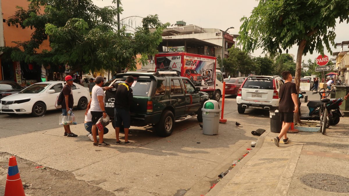 Las personas se aglomeran cerca de los vehículos en la calle Ayacucho