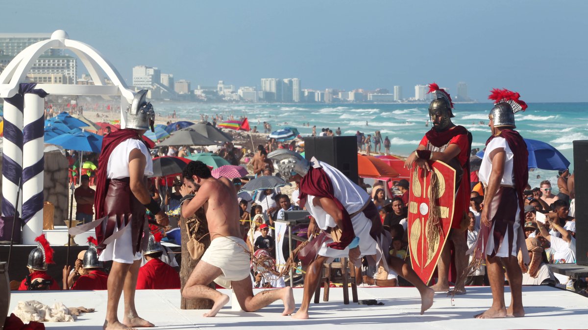 Fieles representan el viacrucis durante la celebración del Viernes Santo en una playa de Cancún (México).