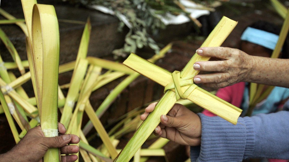 Una mujer compra una cruz de palma de cera, en una fotografía de archivo