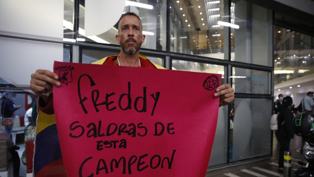 Un aficionado sostiene un cartel de apoyo al exfutbolista colombiano Freddy Rincón, quien sufrió un grave accidente de tráfico en la madrugada de este lunes, hoy, a las afueras de la clínica Imbanaco donde se encuentra hospitalizado, en Cali (Colombia).