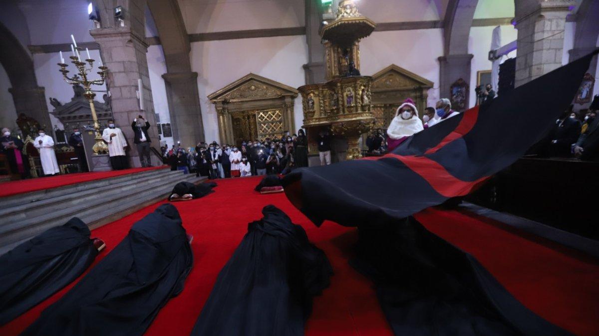 La bandera negra con una cruz roja es ondeada a los ocho canónigos postrados en el suelo.