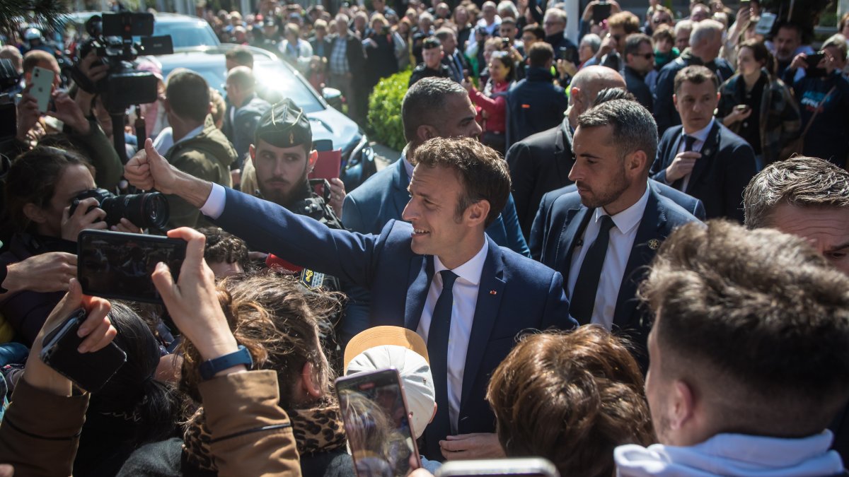 El presidente francés y candidato a la reelección Emmanuel Macron (c) saluda a la gente antes de acudir al colegio electoral en la segunda vuelta de las elecciones presidenciales francesas