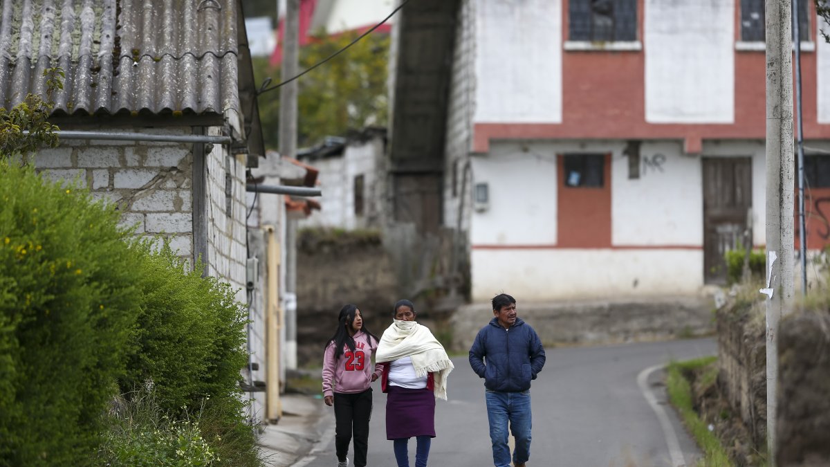 Un grupo de personas camina por una calle vacía, el 9 de abril de 2022, en Ambatillo (Ecuador)