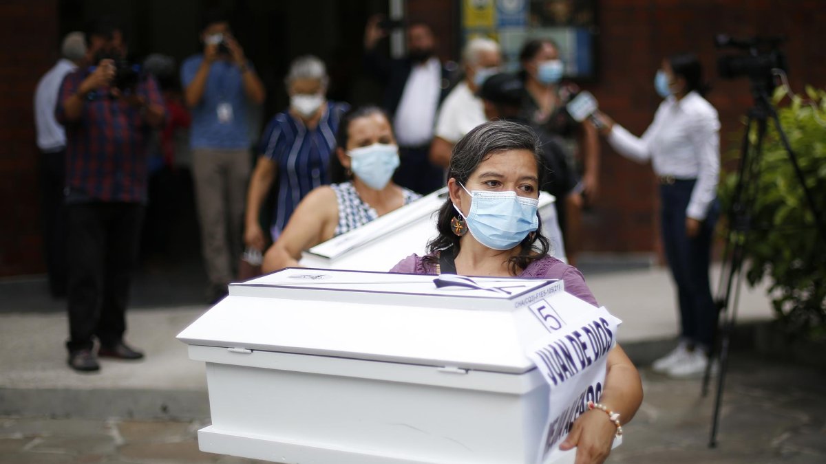 Una mujer lleva el ataúd que contiene las osamentas de un familiar, asesinado 1980 por el ejército salvadoreño, hoy, en San Salvador (El Salvador).