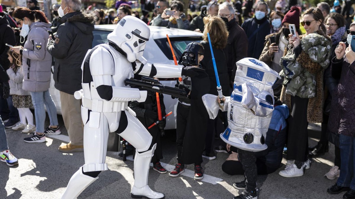 Un soldado de asalto imperial de la saga cinematográfica Star Wars se acerca a dos niños disfrazados mientras participan en el desfile del Galaxy Day, el domingo por una calle de Madrid.