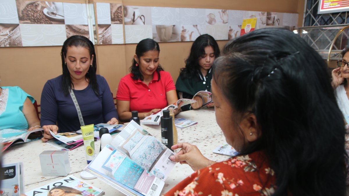 Varias mujeres se reúnen en la cafetería Fredo’s para socializar el contenido de los catálogos.
