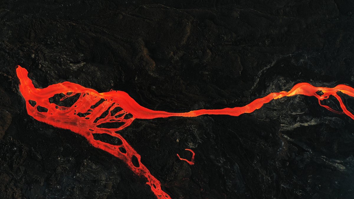 Imagen de archivo tomada con un dron de una colada de magma que discurre hacia el mar rodeada de roca volcánica por la erupción del volcán Cumbre Vieja.