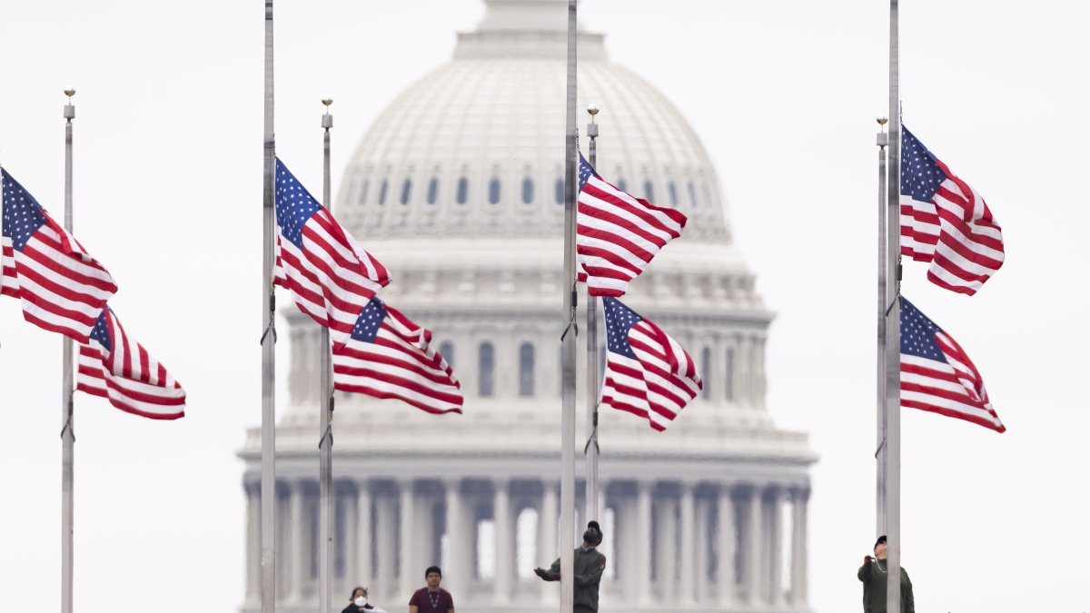 Funcionarios de Parques Nacionales ondean las banderas a media asta, este 12 de mayo de 2022 en Washington, para recordar a los fallecidos por covid-19, que superan el millón de personas en el país