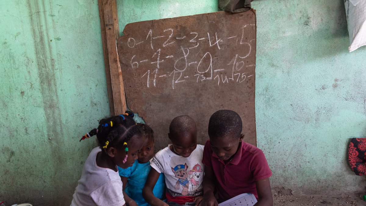 Niños le enseñan hoy a niños de menor edad en un albergue de desplazados internos por la guerra de pandillas, en la comuna de Tabarre, distrito de Puerto Príncipe (Haití).